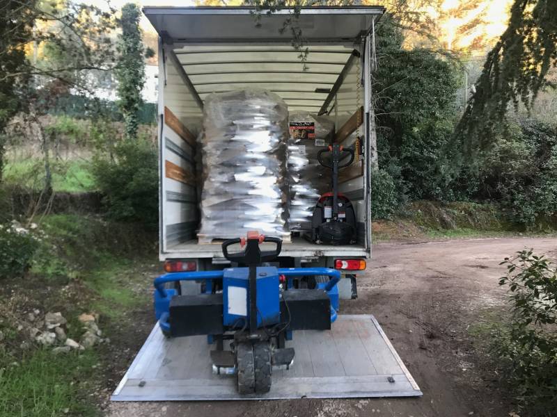 Livraison à domicile de palettes de bois de chauffage, granulés de bois et bûches densifiées avec transpalette électrique tout terrain.
